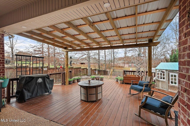 deck featuring area for grilling, an outdoor fire pit, and a storage unit