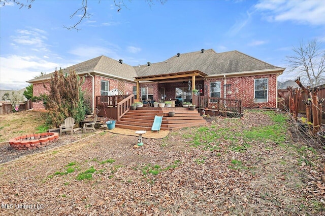 rear view of property featuring a wooden deck and an outdoor fire pit