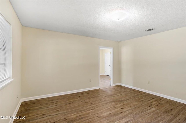 empty room featuring a textured ceiling and dark hardwood / wood-style floors