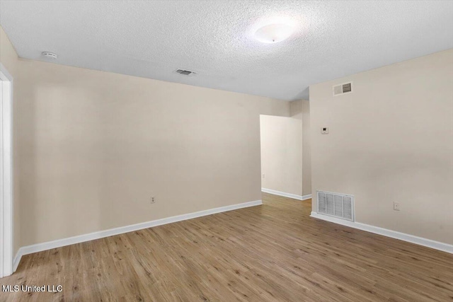 spare room with light hardwood / wood-style floors and a textured ceiling