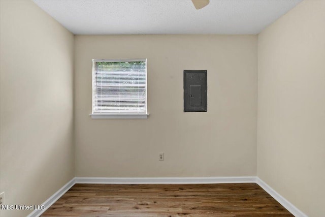 empty room with hardwood / wood-style floors, a textured ceiling, and electric panel