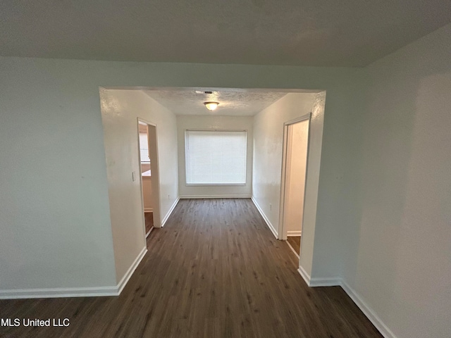 corridor featuring a textured ceiling and dark hardwood / wood-style flooring