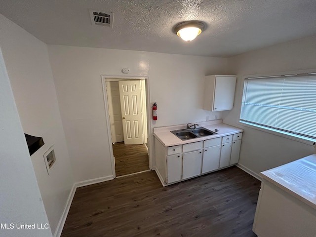 kitchen featuring sink, white cabinetry, dark wood-type flooring, and a textured ceiling