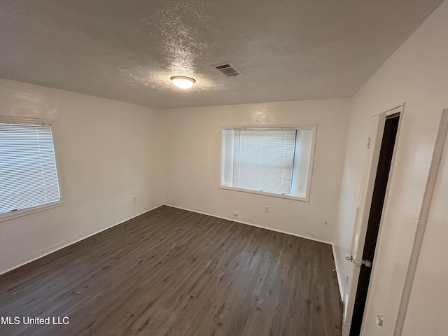 unfurnished room with a textured ceiling and dark hardwood / wood-style floors