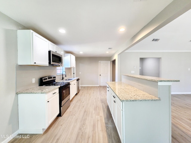 kitchen with a sink, tasteful backsplash, light wood finished floors, and stainless steel appliances