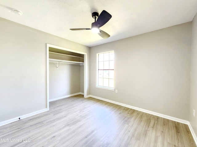 unfurnished bedroom featuring ceiling fan, a closet, baseboards, and wood finished floors