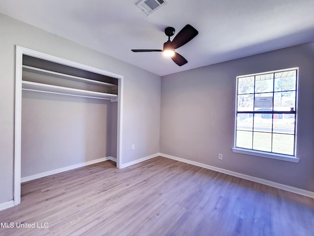 unfurnished bedroom with visible vents, baseboards, a closet, and wood finished floors