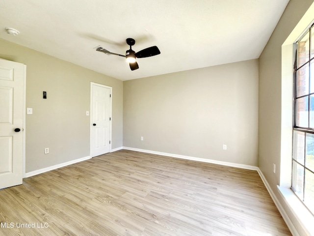 spare room with baseboards, light wood-style floors, and a ceiling fan