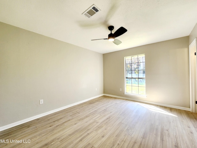 empty room with ceiling fan, light wood-style floors, visible vents, and baseboards