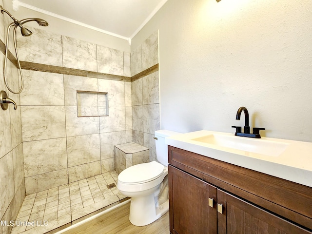 bathroom with tiled shower, toilet, vanity, and crown molding