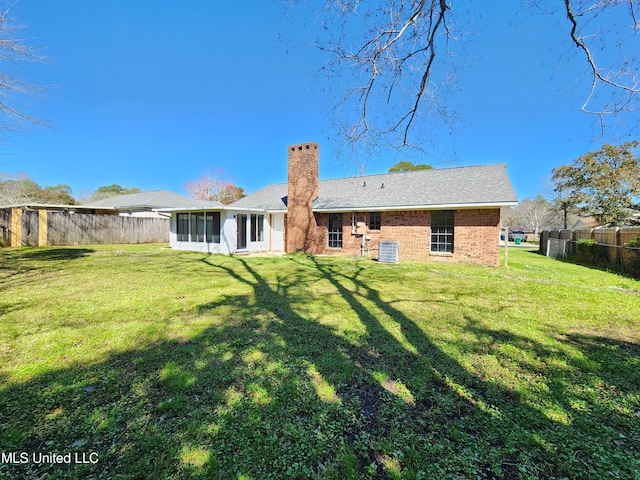 rear view of property with a yard, fence, a chimney, and a sunroom