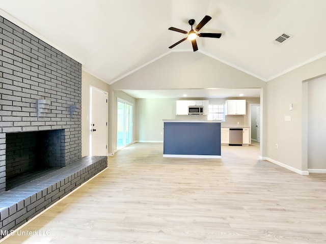 unfurnished living room with a healthy amount of sunlight, baseboards, lofted ceiling, a fireplace, and light wood-style floors