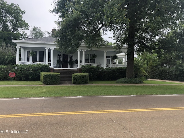 greek revival inspired property featuring covered porch and a front lawn