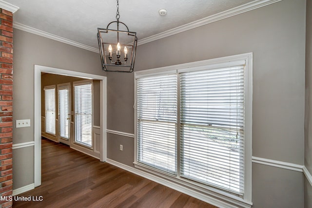 empty room with crown molding, dark hardwood / wood-style floors, and a chandelier