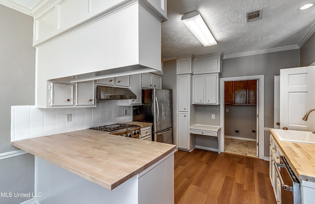 kitchen with butcher block countertops, sink, stainless steel fridge, stove, and a textured ceiling