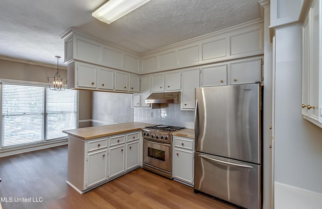 kitchen with pendant lighting, white cabinetry, butcher block counters, ornamental molding, and stainless steel appliances