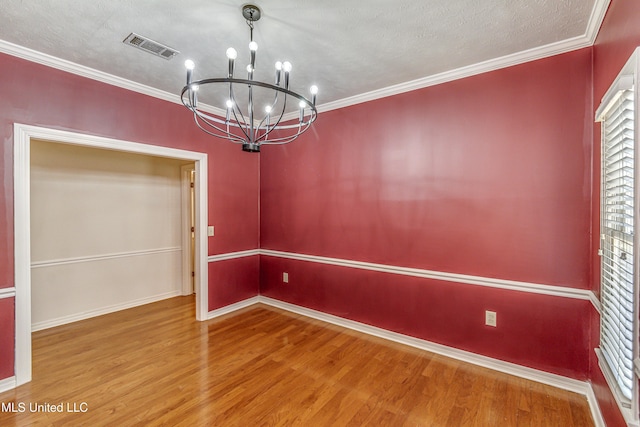 unfurnished dining area featuring wood-type flooring, a textured ceiling, a notable chandelier, and crown molding