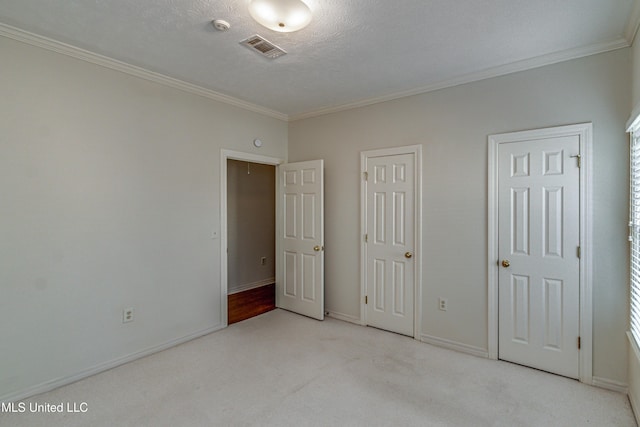 unfurnished bedroom with crown molding, light colored carpet, and a textured ceiling