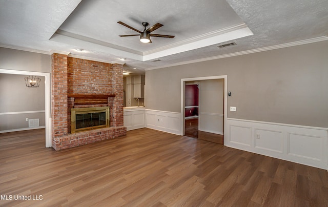 unfurnished living room featuring a tray ceiling, crown molding, a textured ceiling, and hardwood / wood-style flooring