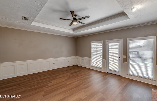 empty room featuring ornamental molding, a raised ceiling, and hardwood / wood-style floors