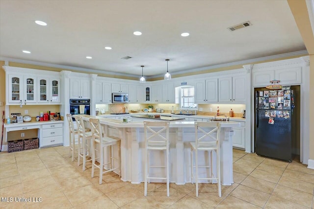 kitchen with a kitchen bar, black appliances, pendant lighting, white cabinets, and a kitchen island