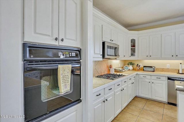 kitchen with white cabinetry, stainless steel appliances, tasteful backsplash, light tile patterned floors, and ornamental molding