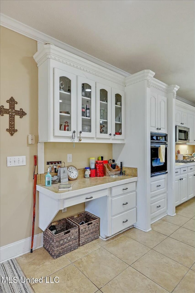 kitchen featuring white cabinetry, crown molding, oven, and light tile patterned flooring