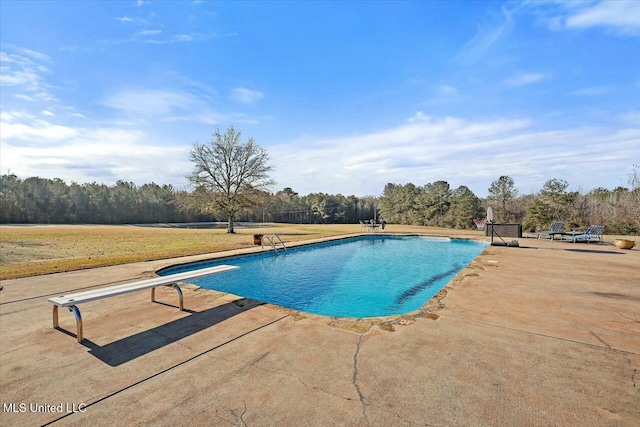 view of swimming pool featuring a patio and a diving board