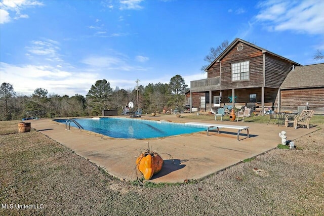 view of swimming pool featuring a diving board and a patio area