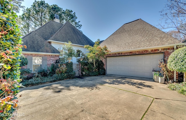 view of front of house with a garage, brick siding, roof with shingles, and a chimney