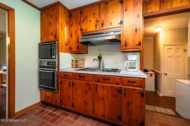 kitchen featuring under cabinet range hood, brick floor, baseboards, and black appliances