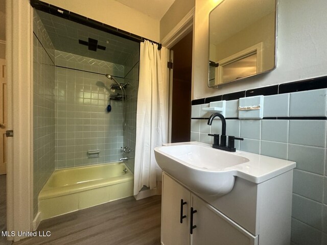 bathroom with tile walls, shower / bath combo with shower curtain, vanity, and wood finished floors