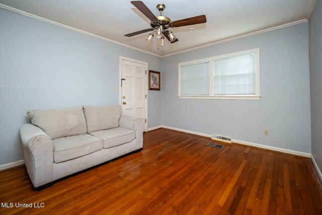living area featuring crown molding, baseboards, wood finished floors, and visible vents