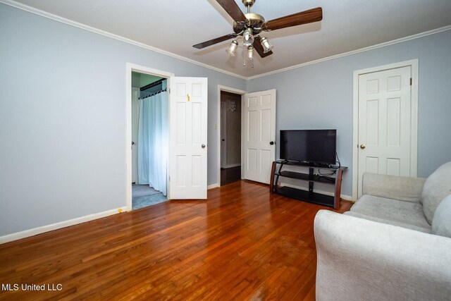 living area with baseboards, crown molding, wood finished floors, and ceiling fan