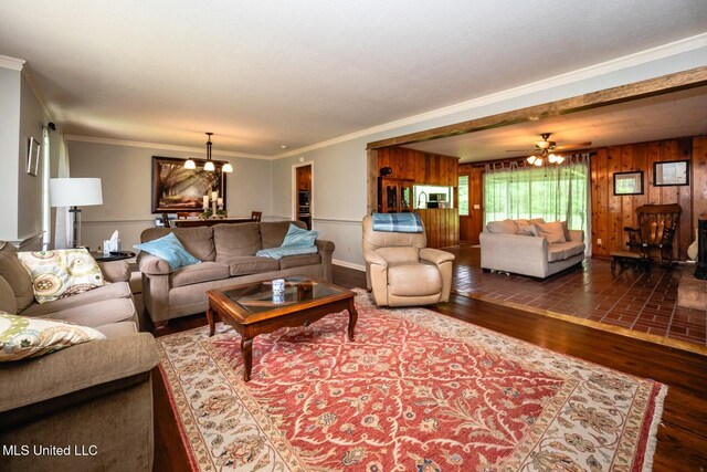 living room featuring ornamental molding, ceiling fan with notable chandelier, wood finished floors, and wooden walls