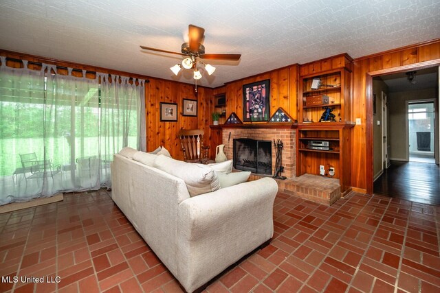 living area featuring a ceiling fan, brick floor, and wooden walls