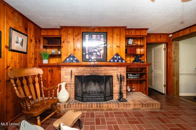 sitting room featuring a brick fireplace, baseboards, wood walls, and brick patterned floor