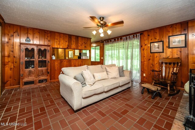 living area with brick floor, wooden walls, and ceiling fan