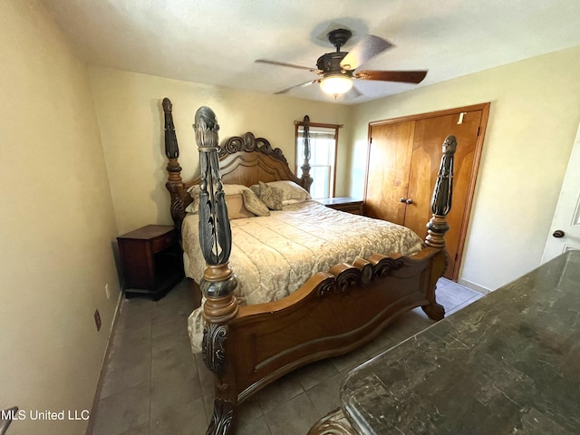 bedroom featuring dark tile patterned floors, ceiling fan, and a closet