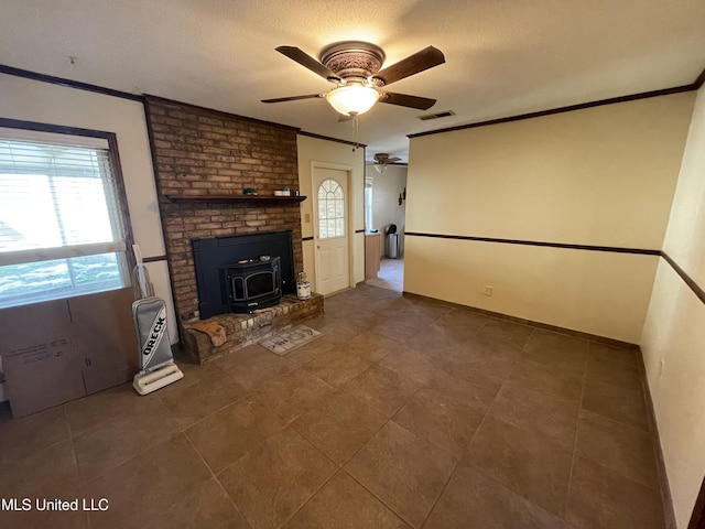 unfurnished living room with ceiling fan, crown molding, and a wood stove