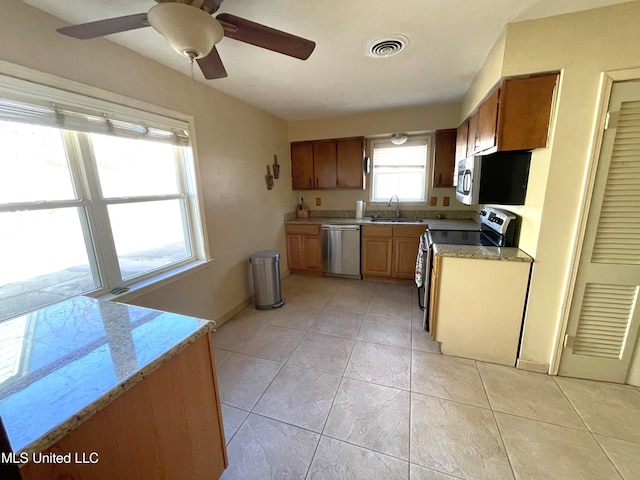 kitchen featuring stainless steel appliances, sink, light tile patterned flooring, ceiling fan, and a wealth of natural light