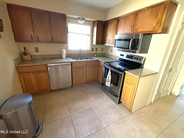 kitchen with stainless steel appliances, light tile patterned floors, and sink