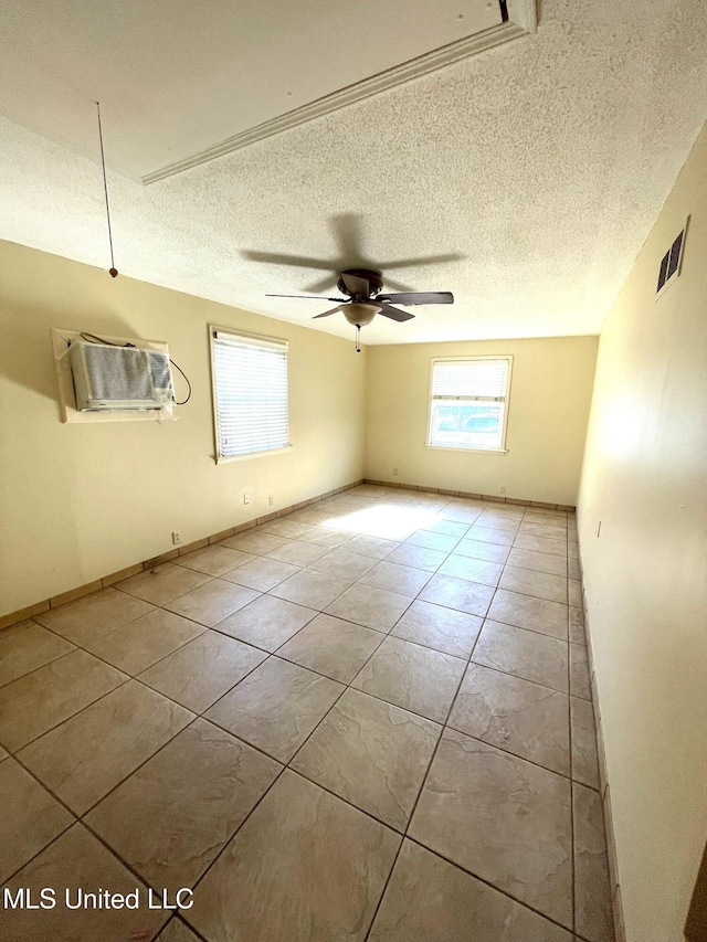 empty room featuring light tile patterned floors, a textured ceiling, ceiling fan, and a wealth of natural light