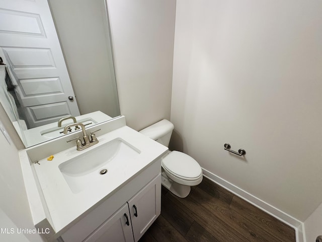 bathroom featuring toilet, wood finished floors, vanity, and baseboards