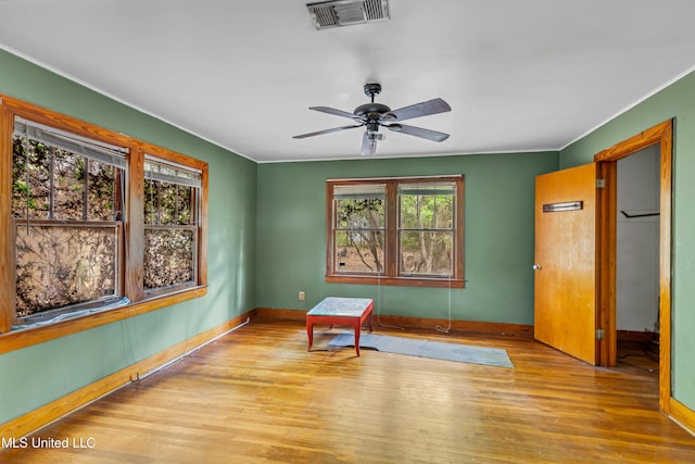 spare room featuring crown molding, wood finished floors, ceiling fan, baseboards, and visible vents