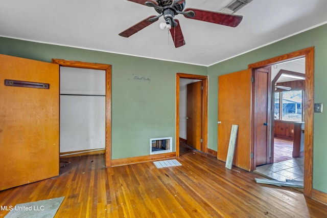empty room featuring hardwood / wood-style floors, a ceiling fan, and visible vents