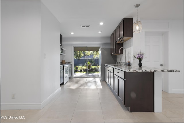 kitchen with sink, dark brown cabinets, stainless steel appliances, light stone countertops, and backsplash