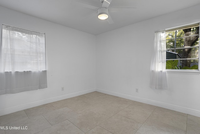 spare room with ceiling fan and light tile patterned flooring