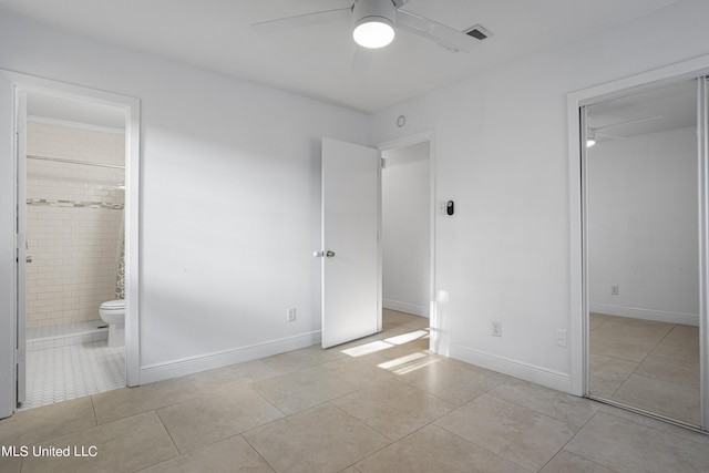 unfurnished bedroom featuring ceiling fan, light tile patterned floors, and ensuite bath