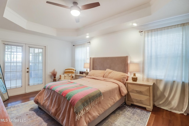 bedroom with wood finished floors, a tray ceiling, access to exterior, and crown molding